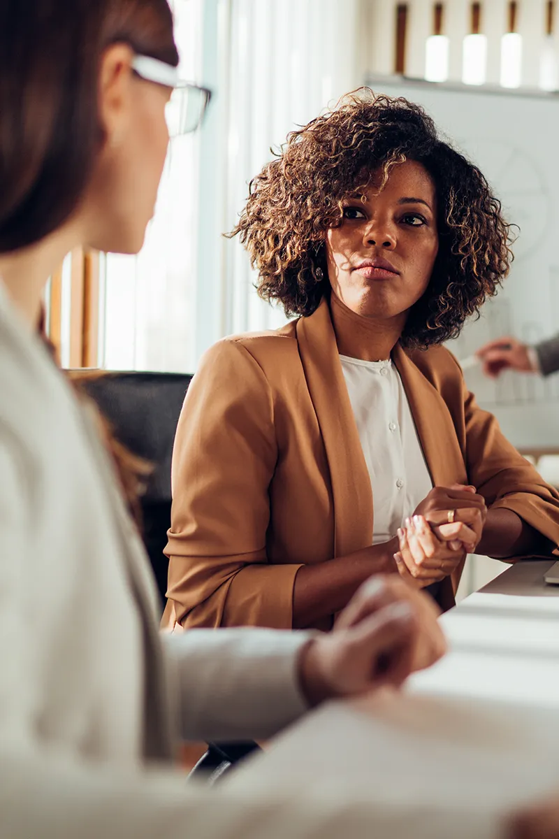 Two businesswomen having a discussion in an office, representing consulting